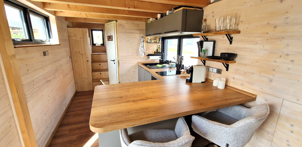 Küche im Tiny House mit Backofen, Mikrowelle, Kühlschrank und Spülmaschine.
