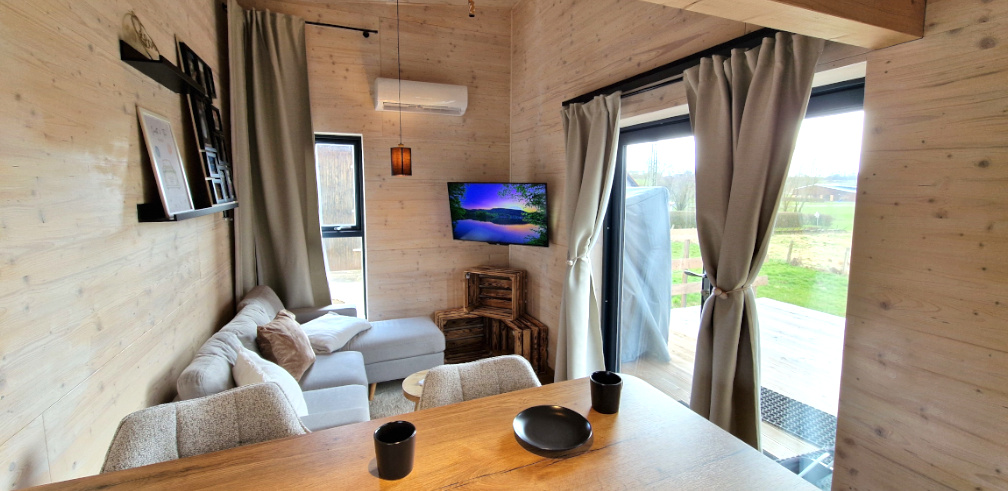 Das Wohnzimmer im Tiny House mit Sofa, TV und Klimaanlage.